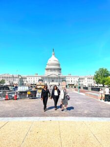 Three people in foreground with entire US Capitol building in background.